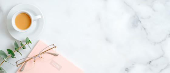 Pink paper notepad, women's glasses, cup of coffee, eucalyptus leaf on marble background with copy space. Beauty blog banner mockup