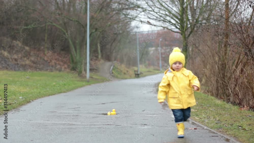 Beautiful funny blonde toddler boy with rubber ducks and colorful umbrella, jumping in puddles and playing in the rain Beautiful funny blonde toddler boy with rubber ducks and colorful umbrella, jumping in puddles and playing in the rain