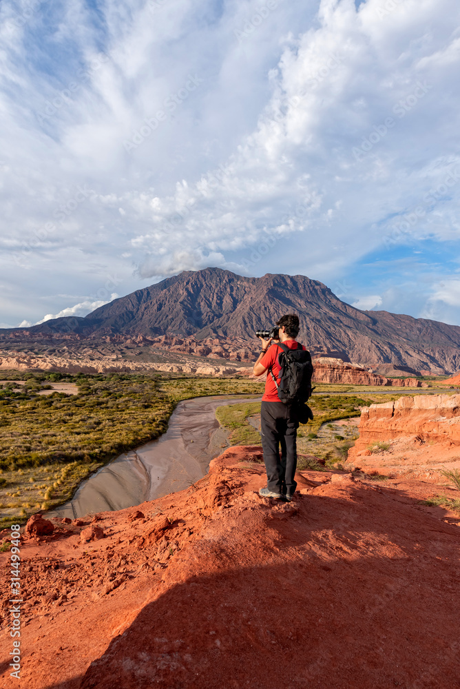 Photographer taking pictures of red earth formations in Quebrada de las Conchas, Salta Region, Argentina