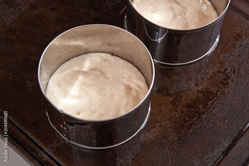 Homemade english muffins with nooks and crannies being cooked on griddle.