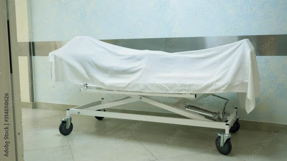 A dead body covered with a white sheet lying on a gurney in a hospital