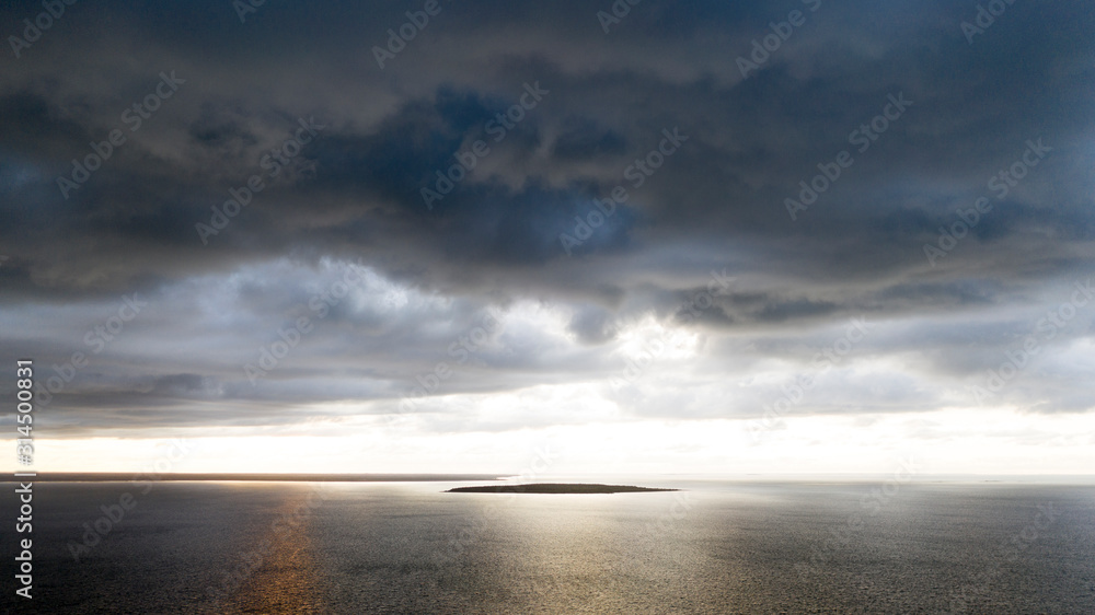 Aerail seascape view with the dark blue rain cloud front on above and bright open sunny sky in the horizon of the destination island 