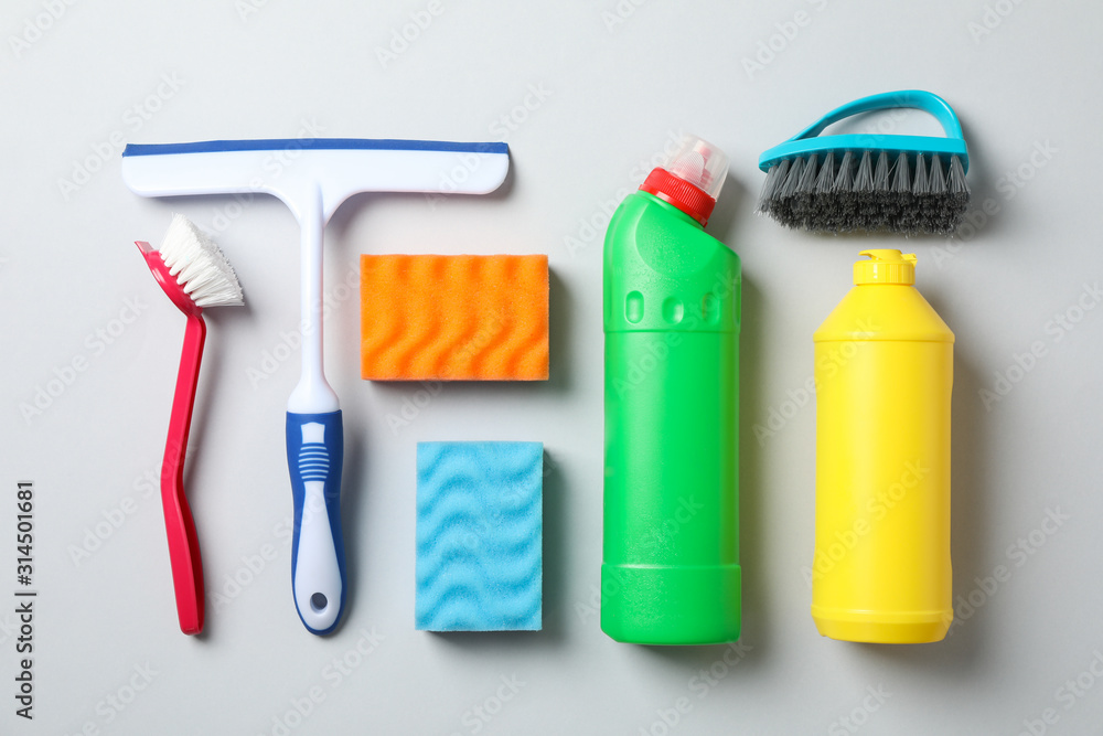 Flat lay with detergents and cleaning supplies on grey background, top view Flat lay with detergents and cleaning supplies on grey background, top view