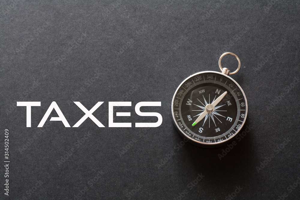 Taxes word written on black background with compass Taxes word written on black background with compass