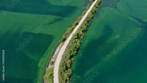 Aerial view of road over the Trebisnjica river, Lastva village, Bosnia and Herzegovina. Turquoise water, green bushes along the road. Minimalism. © dimabucci