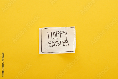 top view of greeting card with happy Easter lettering on yellow colorful background