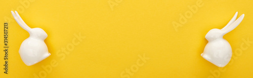 top view of white Easter bunnies on colorful yellow background, panoramic shot