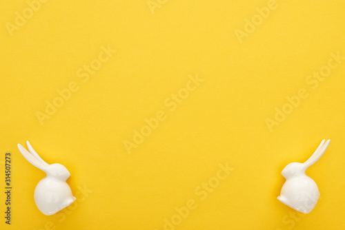 top view of white Easter bunnies on colorful yellow background