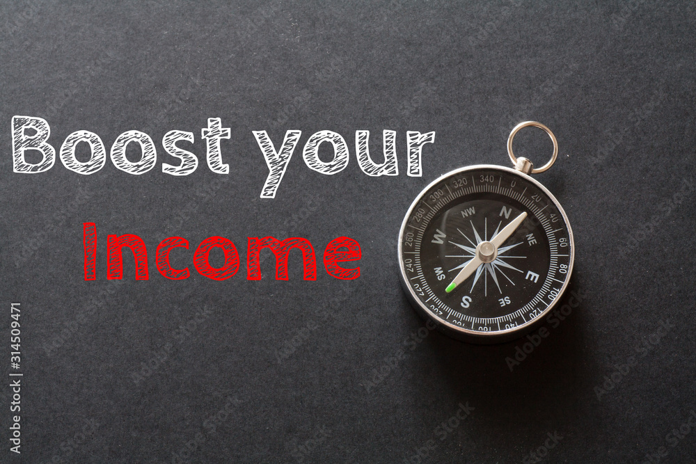 Written Boost your income words on black background with compass Written Boost your income words on black background with compass