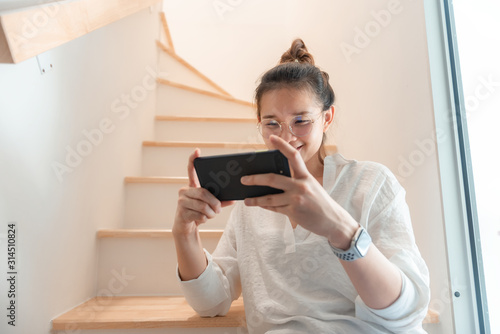 Beautiful women use their smartphones on the stairs in the house.