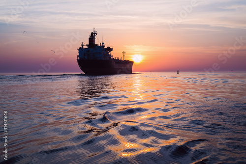 Large cargo ship at sunset. Colorful evening clouds and bright sunlight. Baltic Sea, Latvia © Alex Stemmer