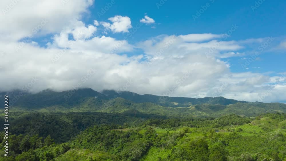 Time lapse: Hills with green grass and blue sky with white puffy clouds. Beautiful landscape on the island of Luzon, aerial view. Time lapse with running clouds over the mountains covered with
