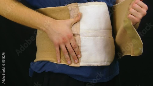 corset, lumbar, spine, put on, belly, waist, man, male, hands, black background, isolated, health, medicine, medical, doctor, heal, recovery