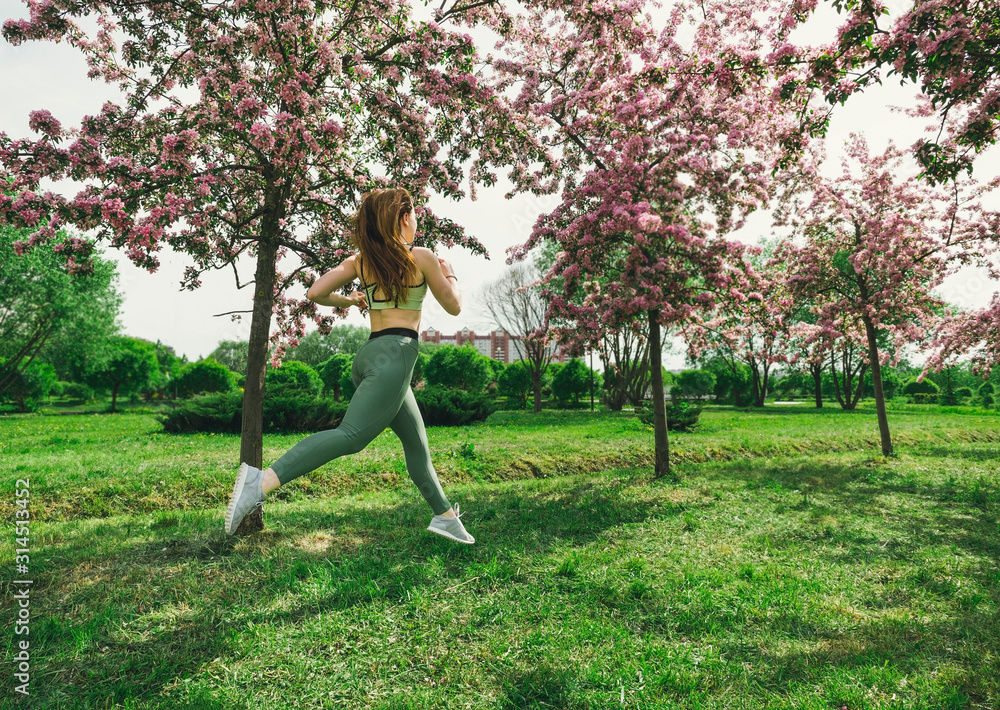 1 white woman with long hair in sports leggings and a top, sneakers, a girl running through a spring blooming Apple orchard 1 white woman with long hair in sports leggings and a top, sneakers, a girl running through a spring blooming Apple orchard