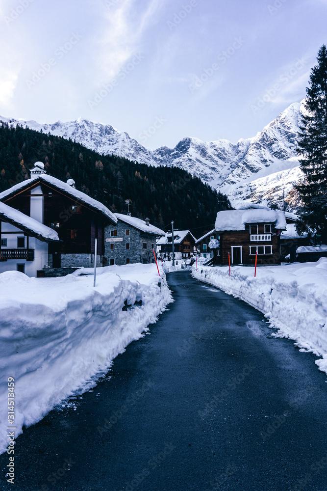 The town of Macugnaga, in the Italian Alps, with its typical houses, the snow and Monte Rosa - December 2019.