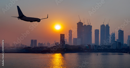 Mumbai is the financial and entertainment capital of India with airplane - Construction crane and skyscraper at sunset