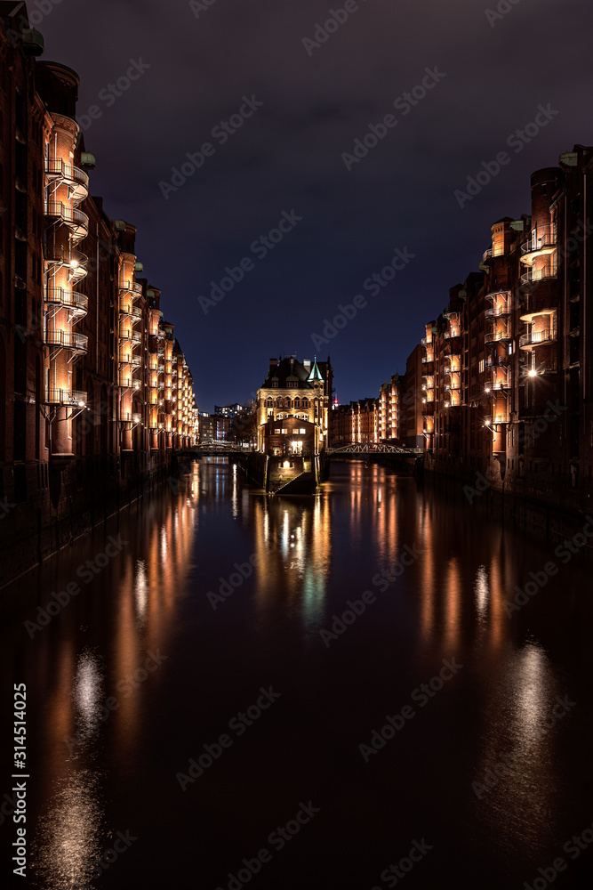 Illuminated Wasserschloss (water castle - famous historic building) in the Speicherstadt (warehouse district) Hamburg after sunset during the blue hour