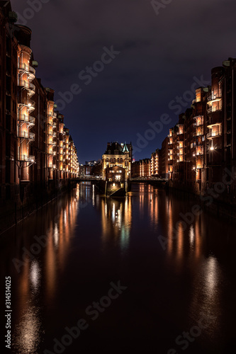 Illuminated Wasserschloss (water castle - famous historic building) in the Speicherstadt (warehouse district) Hamburg after sunset during the blue hour