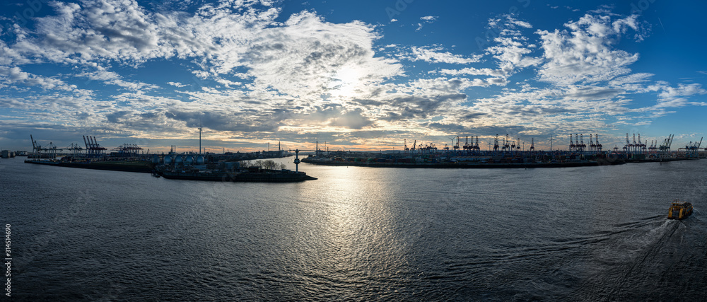 Obraz premium Stunning panoramic view of the Port of Hamburg with the container terminal and the Köhlbrandbrücke bridge at Elbe river at sunset from the roof of Dockland