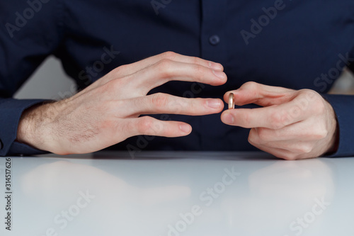 Young man is taking off the wedding ring. Close up view. Divorce concept