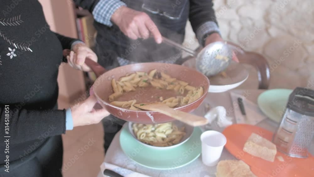 Mature couple serving meal based on cooked pasta Mature couple serving meal based on cooked pasta