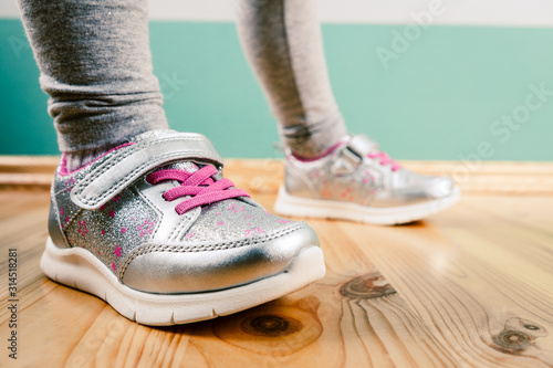 child in sneakers on wooden background