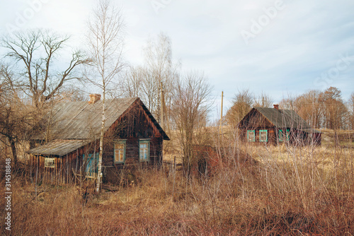 Two old rustic wooden houses in an abandoned village in early spring