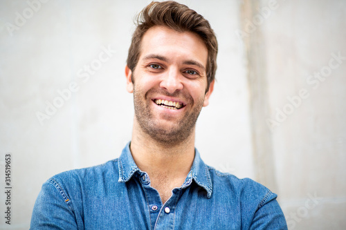  front portrait smiling man with blue shirt by white wall © mimagephotos