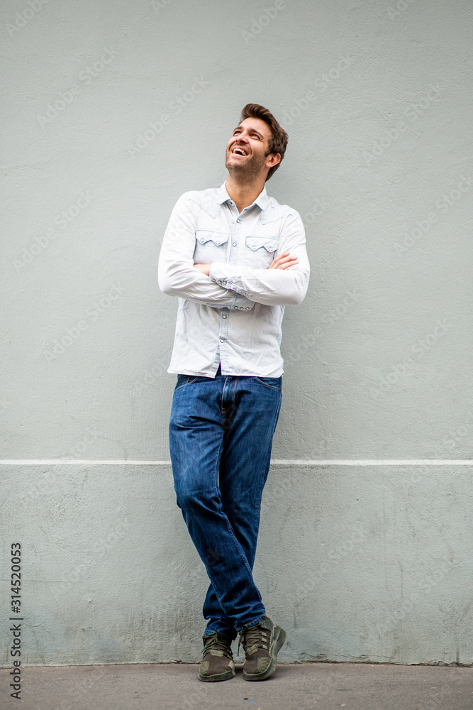 Full length happy older man leaning against wall and with arms crossed and looking up Full length happy older man leaning against wall and with arms crossed and looking up
