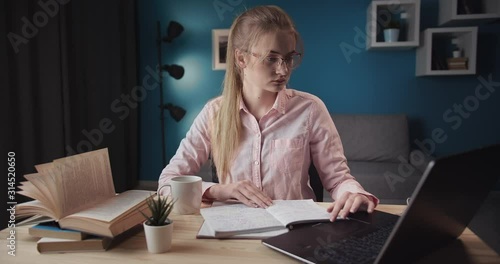 Serious female student in spectacles using laptop for studying forign language, online education photo