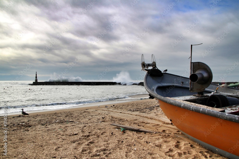 Fishing boats stranded on Aguda beach and Giant waves breaking on the breakwater Fishing boats stranded on Aguda beach and Giant waves breaking on the breakwater
