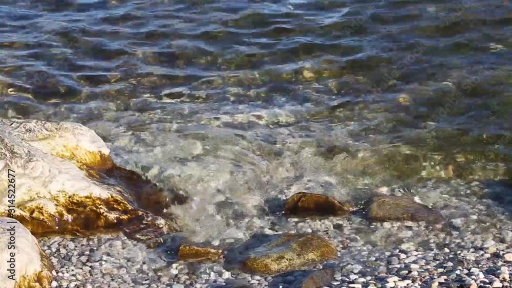 Movement of the transparent and clean water of Lake Garda. Close-up. Staycations concept of tourism in Italy. Movement of the transparent and clean water of Lake Garda. Close-up. Staycations concept of tourism in Italy.