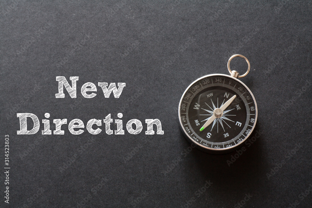 New Direction written with Compass on black paper background New Direction written with Compass on black paper background