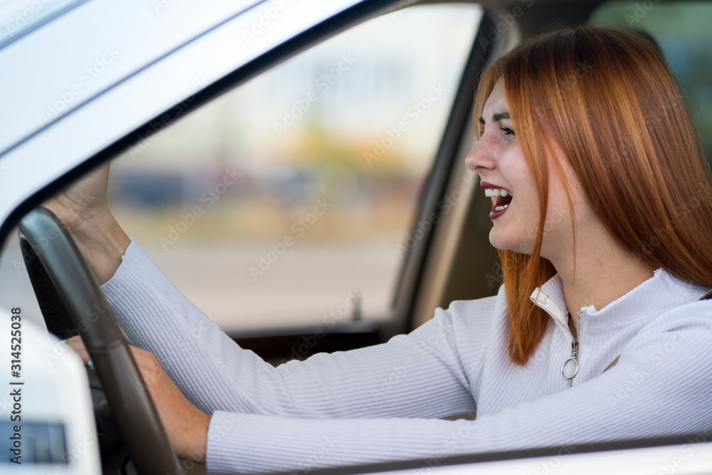 Closeup portrait of pissed off displeased angry aggressive woman driving a car shouting at someone with hand fist up. Negative human expression consept. Closeup portrait of pissed off displeased angry aggressive woman driving a car shouting at someone with hand fist up. Negative human expression consept.