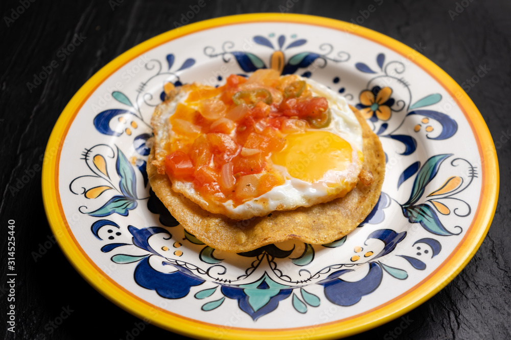 Mexican egg mounted on corn tortilla with sauce also called 