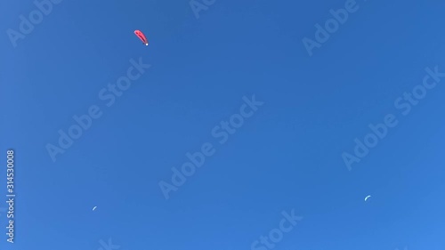 Paragliding on blue sky background. Flying red parachute in the sky