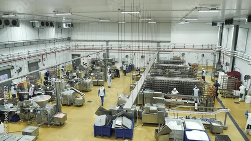 Interior of meat processing plant with equipment and workers in uniform