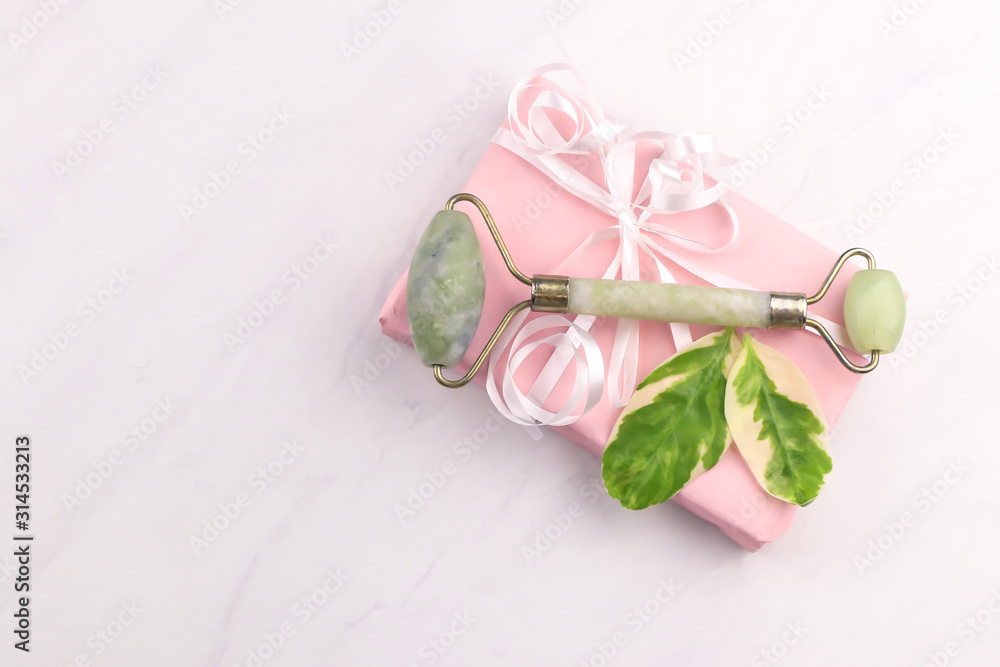 Facial and body stone massage instruments and giftbox on light background Facial and body stone massage instruments and giftbox on light background
