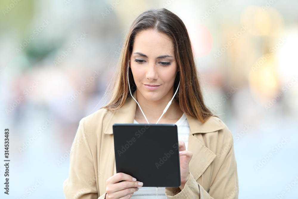 Serious woman e-learning using tablet and earbuds Serious woman e-learning using tablet and earbuds