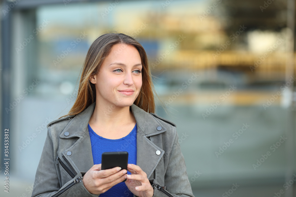Confident woman holding phone looking at side Confident woman holding phone looking at side