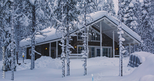 Valokuva A cozy wooden cabin cottage chalet house covered in snow near ski resort in wint