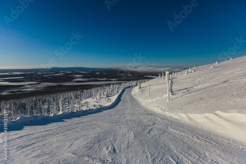 Beautiful vibrant aerial winter mountain view of ski resort, sunny winter day with slope, piste and ski lift © tsuguliev