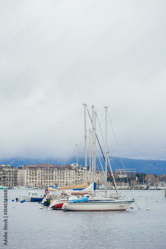 Beautiful yachts at the water port in European town, travel, tourism and vacation concept. Photography with white boats and the city lake on cloudy sky background.