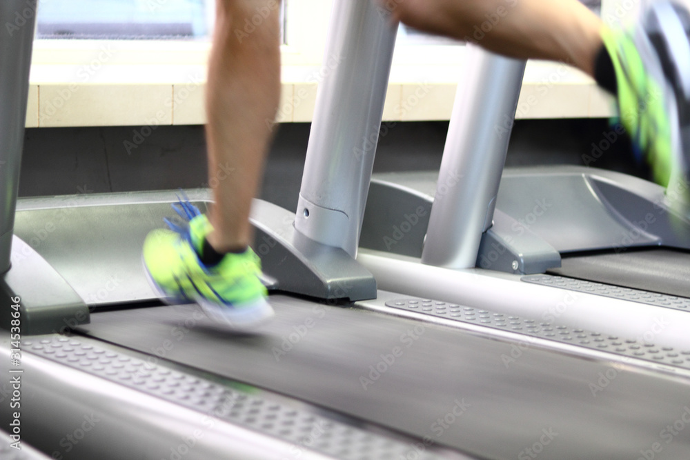 Male Runner Running on Treadmill in Gym. Focus on leg. Male Runner Running on Treadmill in Gym. Focus on leg.