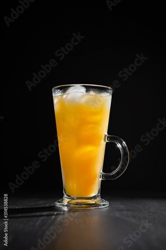  glass of fresh orange juice with ice on a black background with a place for inscription