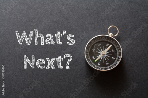 Written What's Next words on black background with compass