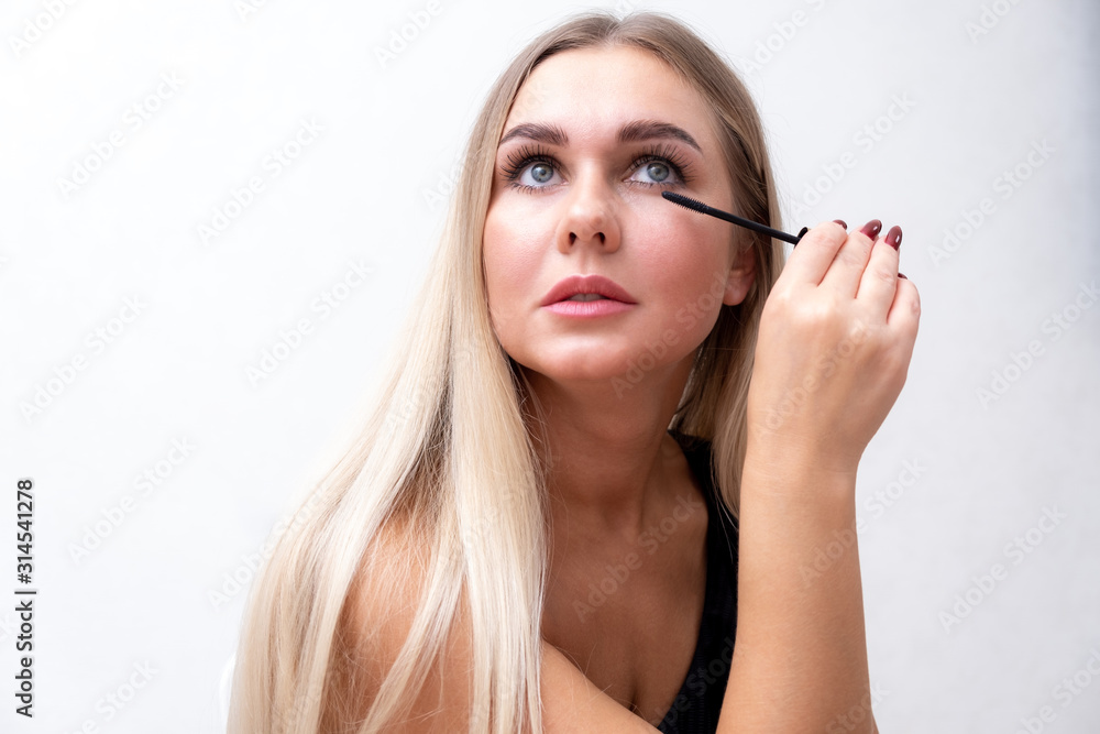 Headshot of female with bright makeup applying mascara on eyelashes. Headshot of female with bright makeup applying mascara on eyelashes.