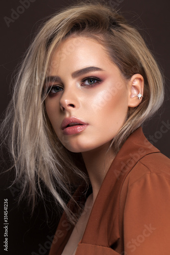 A very beautiful young blonde model with professional make up, perfect skin. Trendy red toned smokey eyes and nude lips.
