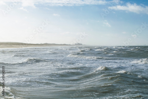 Low tide and stormy weather at beach near the Hague, the Netherlands, featuring blue skies and waves. North Sea natural background in January.