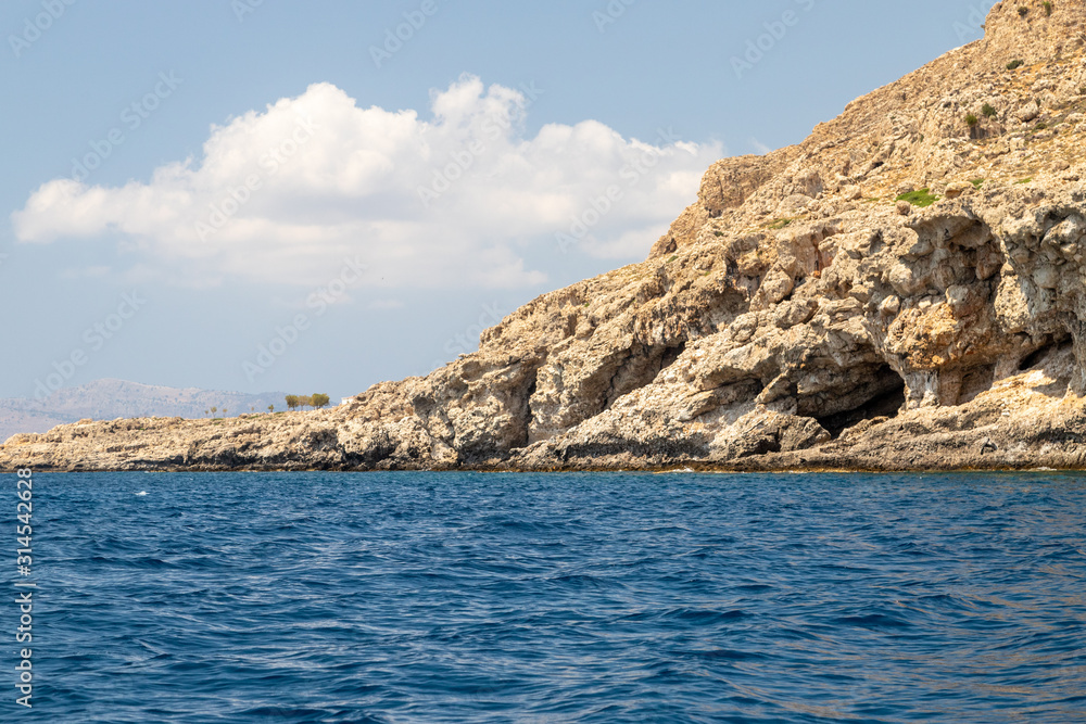 View from a motor boat on the mediterranean sea at the rocky coastline near Stegna on the eastside of Greek island Rhodes